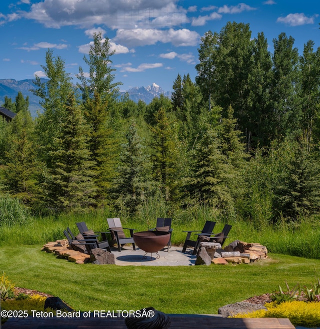 5060 W Eagle Rd, Wilson, WY 83014 - view of green lawn with a patio area, a mountain view, and a fire pit