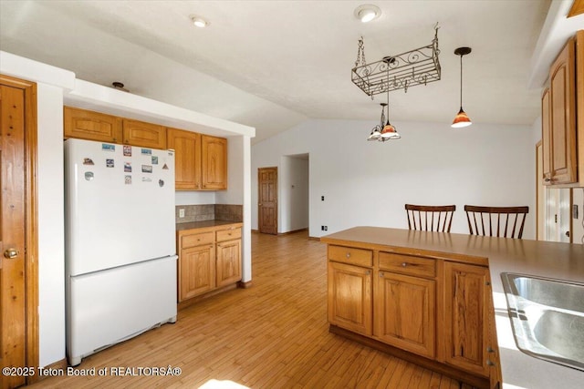 7302 Lakeside Rd, Victor, ID 83455 - kitchen featuring freestanding refrigerator, vaulted ceiling, hanging light fixtures, light wood-style flooring, and brown cabinets