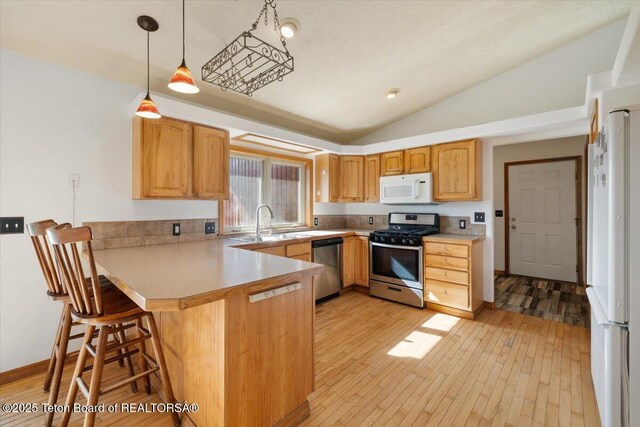 7302 Lakeside Rd, Victor, ID 83455 - kitchen with stainless steel appliances, lofted ceiling, a peninsula, light wood finished floors, and decorative light fixtures