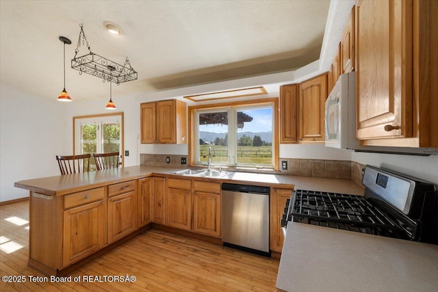 7302 Lakeside Rd, Victor, ID 83455 - kitchen featuring stainless steel appliances, a peninsula, hanging light fixtures, light wood-style floors, and light countertops