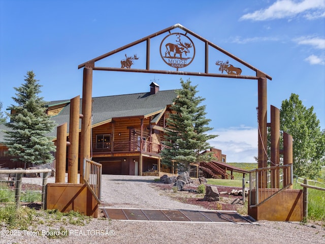 1802 Dusty Trl, Auburn, WY 83111 - cabin featuring roof with shingles, a garage, a chimney, and gravel driveway