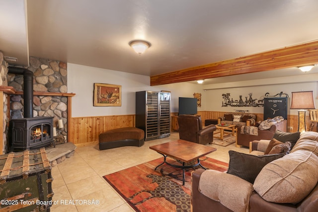 1802 Dusty Trl, Auburn, WY 83111 - living room featuring wainscoting, wooden walls, light tile patterned floors, a wood stove, and beamed ceiling