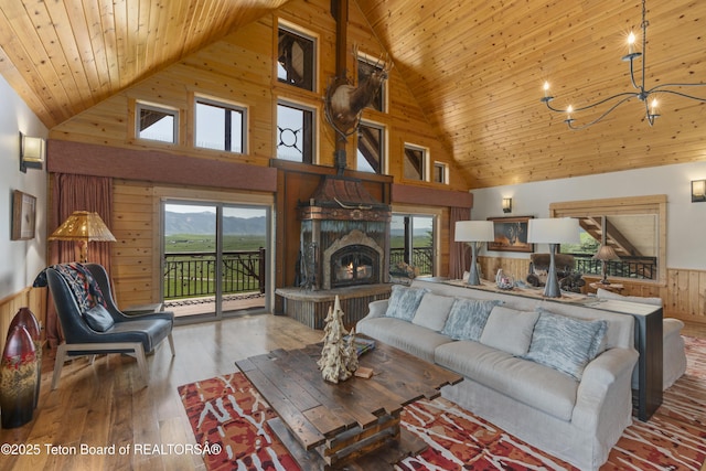 1802 Dusty Trl, Auburn, WY 83111 - living room with wood walls, high vaulted ceiling, a chandelier, wood ceiling, and a warm lit fireplace
