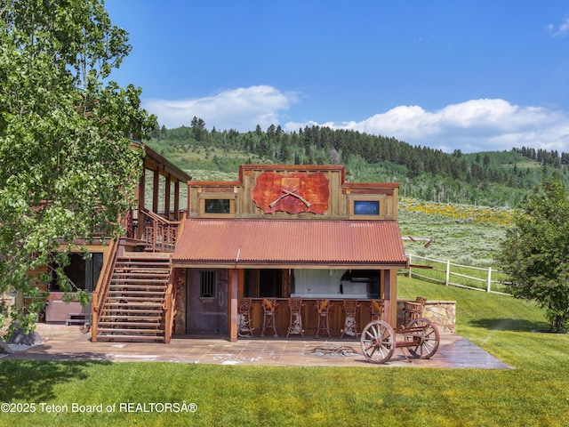 1802 Dusty Trl, Auburn, WY 83111 - rear view of property with a view of trees, a patio area, a metal roof, and a wooden deck