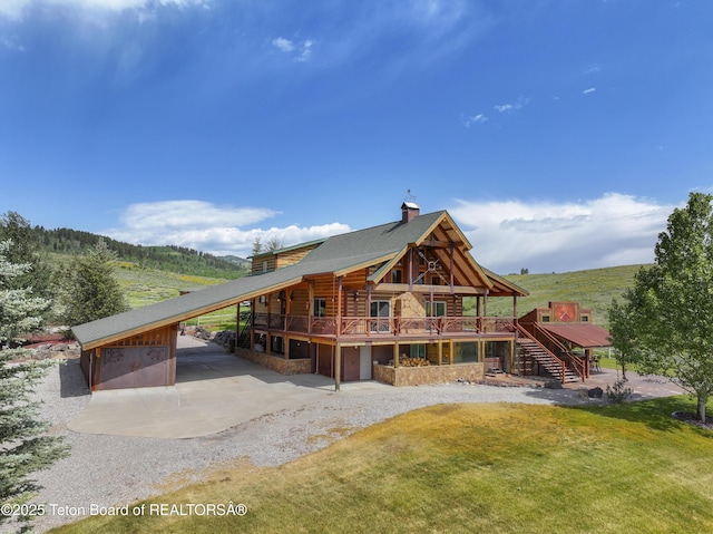 1802 Dusty Trl, Auburn, WY 83111 - back of house with stairs, a deck, driveway, a chimney, and stone siding