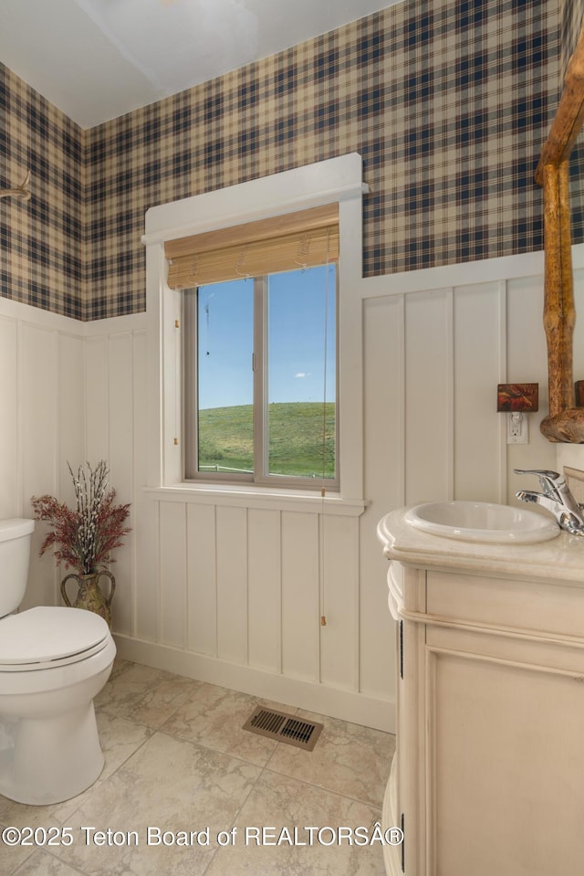 1802 Dusty Trl, Auburn, WY 83111 - bathroom featuring a decorative wall, vanity, wallpapered walls, wainscoting, and marble finish floors