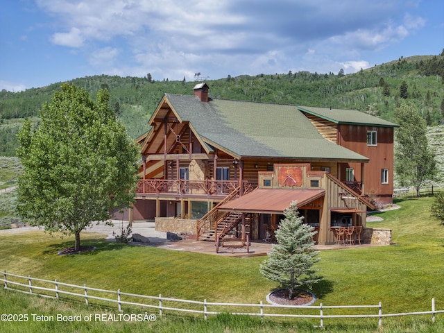 1802 Dusty Trl, Auburn, WY 83111 - back of house featuring a patio, a chimney, a deck with mountain view, stairs, and a forest view