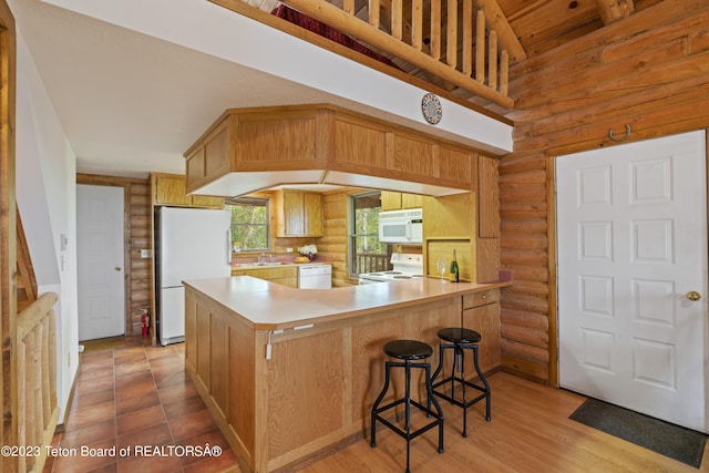 4821 S 2000 E, Victor, ID 83455 - kitchen featuring white appliances, rustic walls, light countertops, a peninsula, and a breakfast bar