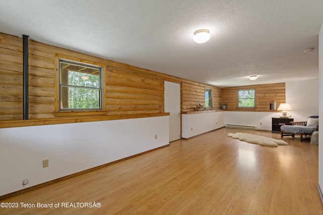 4821 S 2000 E, Victor, ID 83455 - unfurnished room featuring a baseboard heating unit, log walls, a textured ceiling, and wood finished floors