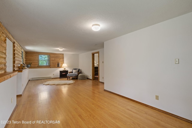 4821 S 2000 E, Victor, ID 83455 - unfurnished living room featuring baseboard heating, light wood-type flooring, a textured ceiling, and log walls
