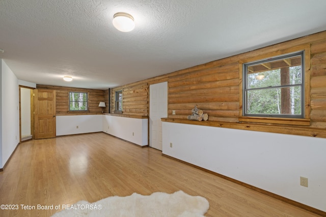 4821 S 2000 E, Victor, ID 83455 - unfurnished room with log walls, a textured ceiling, and light wood-style flooring