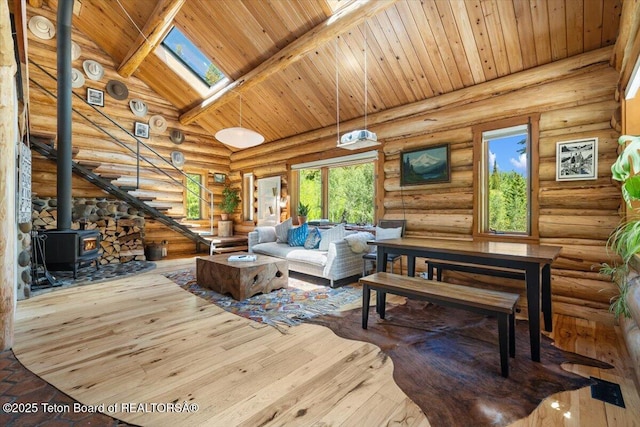 6250 W Paintbrush Trl, Wilson, WY 83014 - living room featuring rustic walls, a wooden ceiling with exposed beams, a wood stove, hardwood / wood-style floors, and a skylight