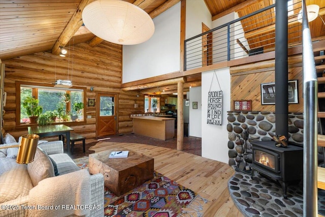 6250 W Paintbrush Trl, Wilson, WY 83014 - living area featuring rustic walls, wood-type flooring, a wood stove, high vaulted ceiling, and a wooden ceiling with exposed beams