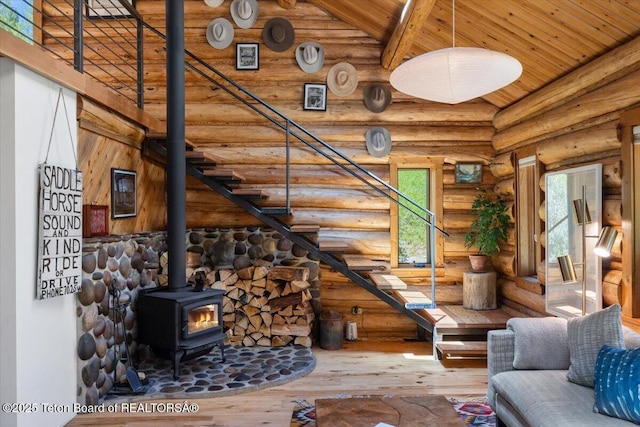 6250 W Paintbrush Trl, Wilson, WY 83014 - living room with rustic walls, a wooden ceiling with exposed beams, hardwood / wood-style flooring, a wood stove, and stairway
