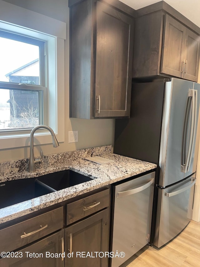 140 Homestead Rd Unit 508, Victor, ID 83455 - kitchen featuring stainless steel appliances, dark brown cabinets, light stone countertops, and light wood-style floors