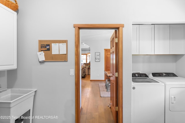 92 Ashley Dr, Alpine, WY 83128 - laundry room featuring cabinet space, independent washer and dryer, light wood-style floors, and arched walkways