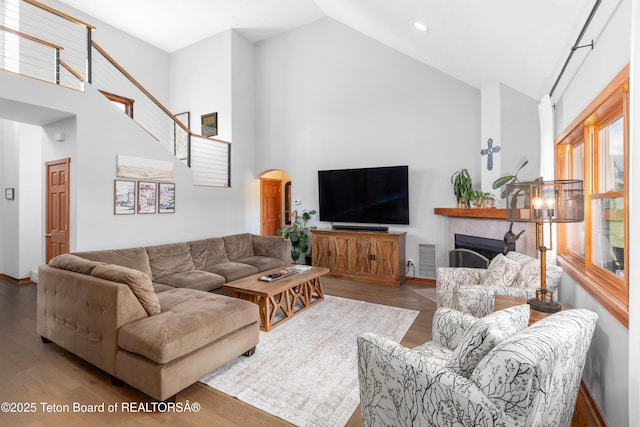 92 Ashley Dr, Alpine, WY 83128 - living area featuring high vaulted ceiling, a fireplace, arched walkways, wood finished floors, and stairway