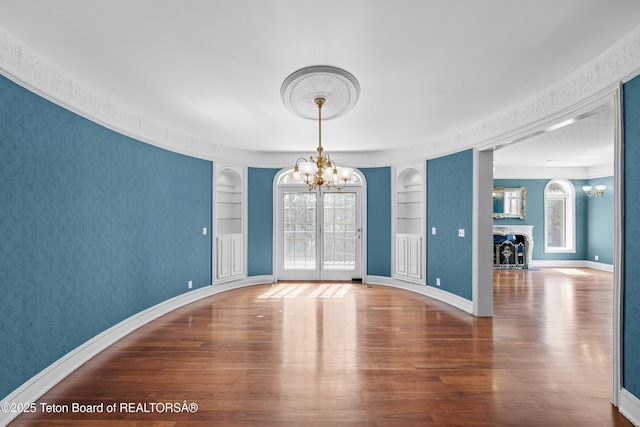 4976 S 49th, Idaho Falls, ID 83406 - empty room featuring a chandelier, built in shelves, wood finished floors, and healthy amount of natural light