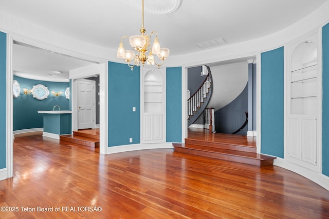 4976 S 49th, Idaho Falls, ID 83406 - unfurnished dining area featuring built in shelves, stairs, a chandelier, and wood finished floors