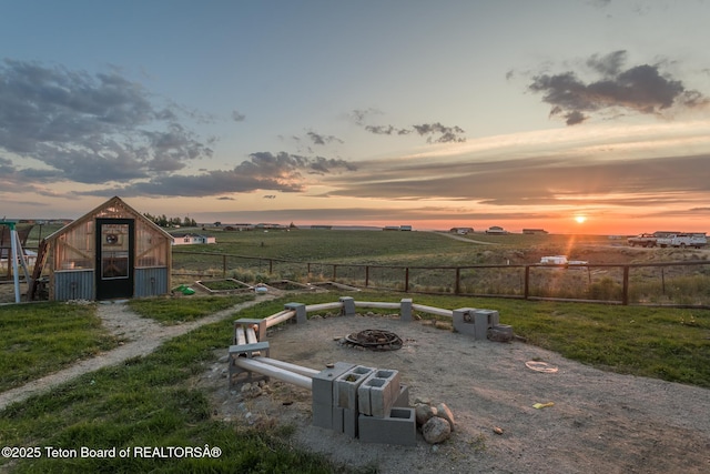 26 Merrimac Trl, Boulder, WY 82923 - yard at dusk featuring a greenhouse, a fire pit, an outbuilding, and a rural view