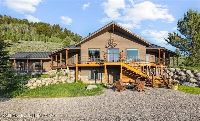 20 Trail Ride Ln, Cora, WY 82925 - view of front of house with a standing seam roof, stairway, stone siding, a metal roof, and a wooden deck