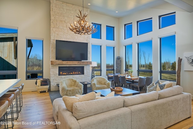 9632 Little Pine Ln, Victor, ID 83455 - living room with wood finished floors, a stone fireplace, a chandelier, recessed lighting, and a towering ceiling