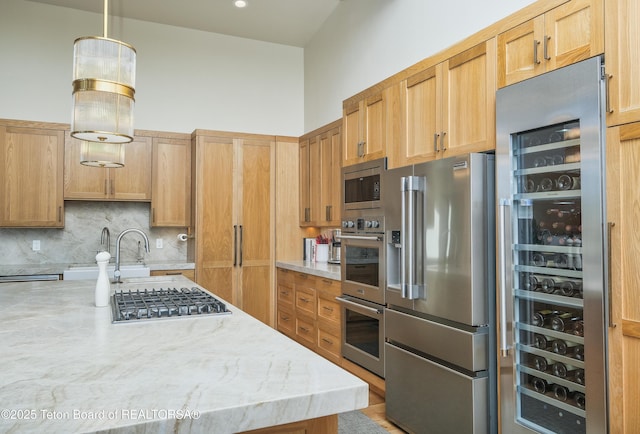 9632 Little Pine Ln, Victor, ID 83455 - kitchen with appliances with stainless steel finishes, wine cooler, decorative backsplash, light stone countertops, and decorative light fixtures