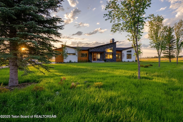 9346 Basin Dr, Victor, ID 83455 - view of front of house with stone siding, a chimney, and a front yard