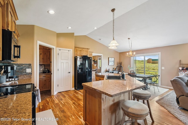3 Healers, Pinedale, WY 82941 - kitchen featuring black appliances, light wood-style flooring, a breakfast bar, lofted ceiling, and a chandelier