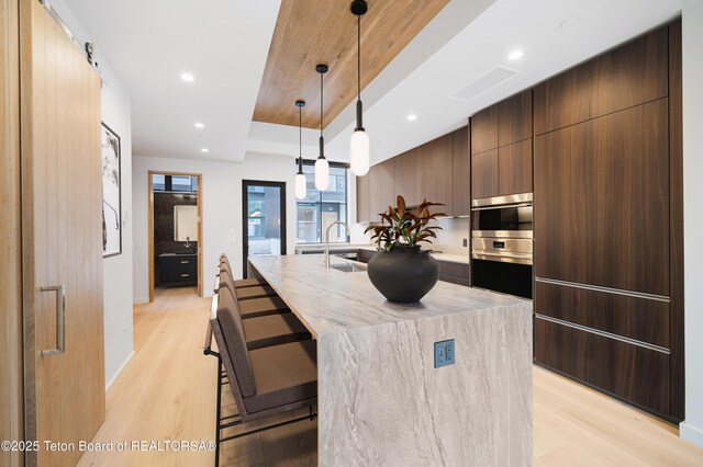 165 N Glenwood St # 30, Jackson, WY 83001 - kitchen featuring light wood-type flooring, modern cabinets, an island with sink, pendant lighting, and recessed lighting