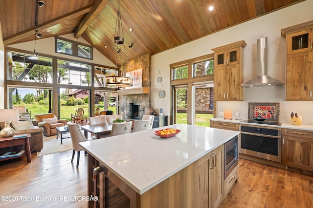 5862 N Coneflower Dr Unit 17, Jackson, WY 83001 - kitchen featuring appliances with stainless steel finishes, wall chimney range hood, a wood ceiling with exposed beams, a fireplace, and high vaulted ceiling