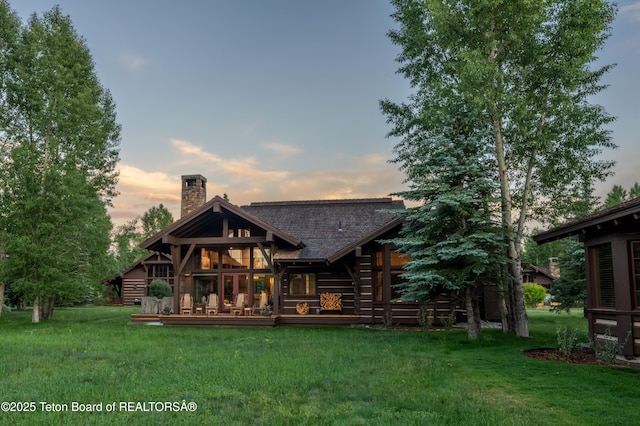 5862 N Coneflower Dr Unit 17, Jackson, WY 83001 - back of property at dusk with a chimney, a yard, and a wooden deck