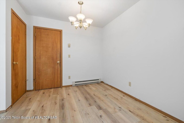 816 Powderhorn Ln Unit 816D, Jackson, WY 83001 - spare room featuring a baseboard heating unit, a chandelier, and light wood-type flooring