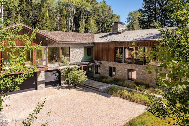 7970 N Granite Ridge Rd, Teton Village, WY 83025 - view of front facade with stone siding, decorative driveway, a chimney, and an attached garage