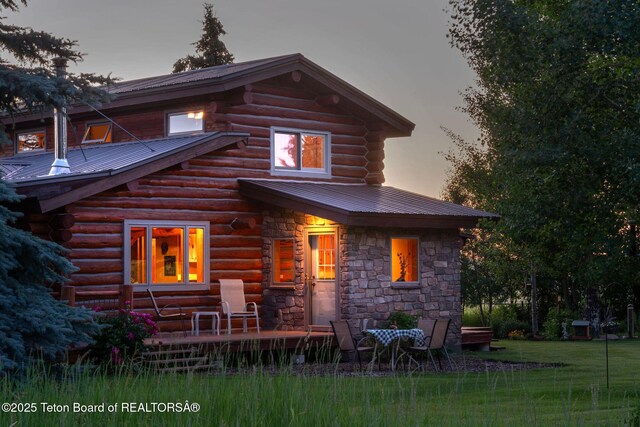 5100 Country Club Dr, Victor, ID 83455 - back of property at dusk featuring log exterior, a metal roof, and stone siding