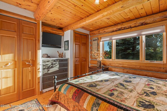 5100 Country Club Dr, Victor, ID 83455 - bedroom featuring light wood-style flooring, two closets, a wood ceiling with exposed beams, and rustic walls