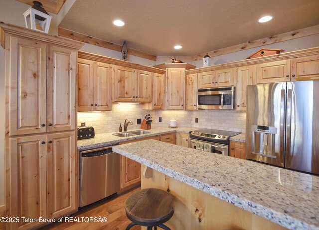 122 Hastings Dr Unit 207, Victor, ID 83455 - kitchen with appliances with stainless steel finishes, light brown cabinetry, a breakfast bar area, recessed lighting, and tasteful backsplash