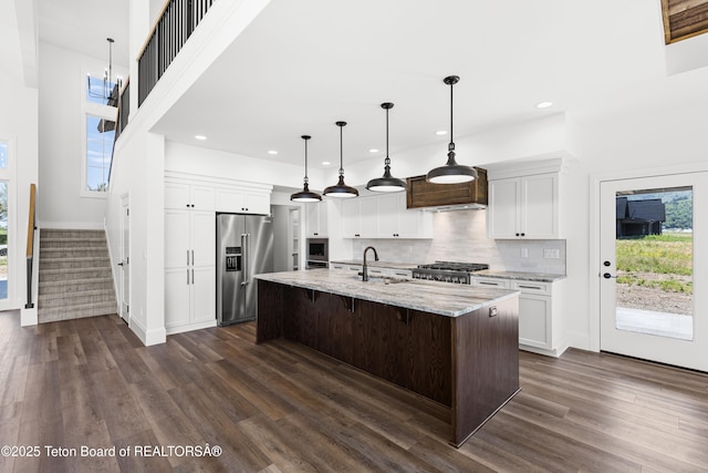 555 Silver Fox Ln, Victor, ID 83455 - kitchen with high end refrigerator, stove, dark wood finished floors, backsplash, and light stone counters