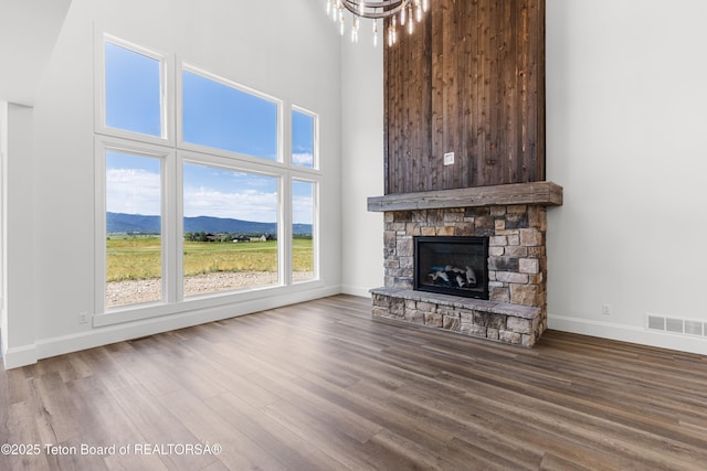 555 Silver Fox Ln, Victor, ID 83455 - unfurnished living room featuring wood finished floors, a mountain view, a stone fireplace, a chandelier, and a towering ceiling