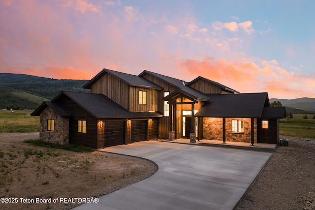 555 Silver Fox Ln, Victor, ID 83455 - view of front of home featuring stone siding, driveway, a mountain view, and a garage