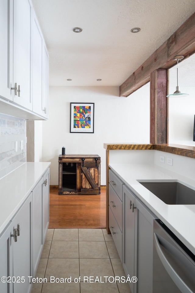 3885 S Lake Creek Dr Unit 1013, Wilson, WY 83014 - kitchen featuring stainless steel dishwasher, light countertops, white cabinetry, light tile patterned floors, and backsplash
