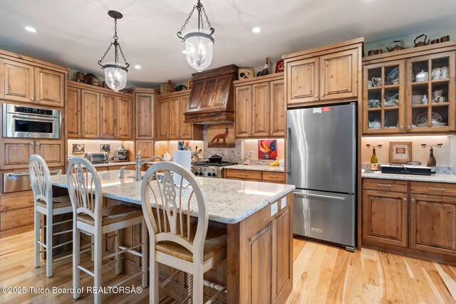6289 Fox Meadows Dr, Victor, ID 83455 - kitchen with appliances with stainless steel finishes, custom exhaust hood, light stone counters, recessed lighting, and glass insert cabinets