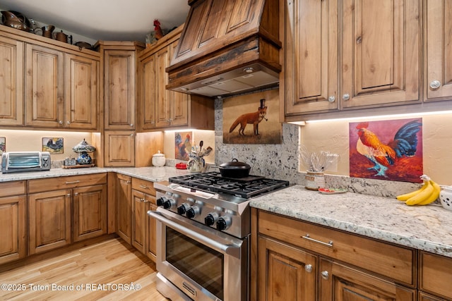 6289 Fox Meadows Dr, Victor, ID 83455 - kitchen with high end stainless steel range oven, brown cabinets, light stone counters, and light wood-style flooring