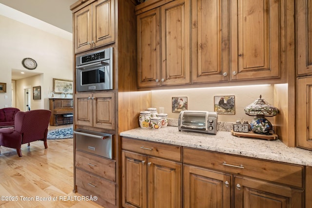 6289 Fox Meadows Dr, Victor, ID 83455 - kitchen with a warming drawer, brown cabinets, and light stone counters