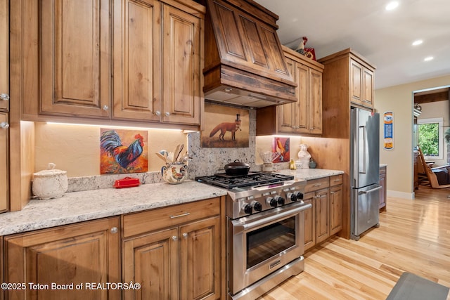 6289 Fox Meadows Dr, Victor, ID 83455 - kitchen with high quality appliances, custom range hood, light wood finished floors, backsplash, and light stone counters