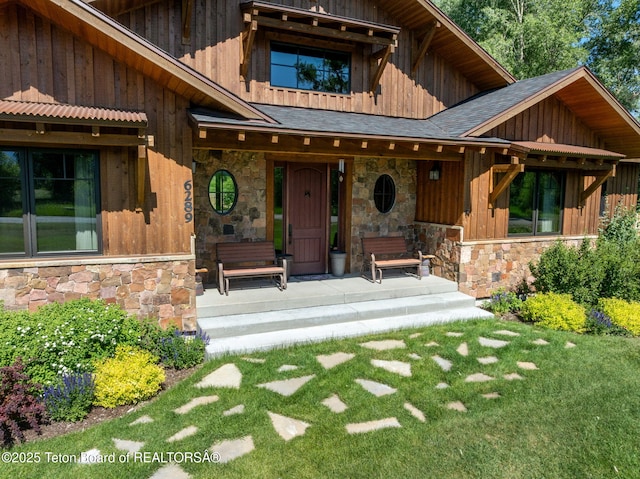 6289 Fox Meadows Dr, Victor, ID 83455 - view of front of home featuring stone siding, covered porch, a front lawn, roof with shingles, and board and batten siding