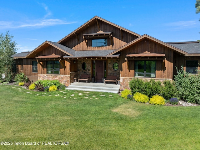 6289 Fox Meadows Dr, Victor, ID 83455 - view of front of house with a porch, stone siding, a front yard, and a shingled roof