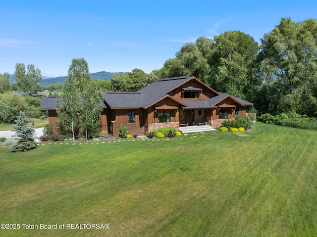 6289 Fox Meadows Dr, Victor, ID 83455 - view of front of home with a front yard, covered porch, roof with shingles, and stone siding