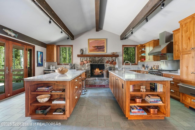 750 N Bar Y Rd, Jackson, WY 83001 - kitchen with open shelves, rail lighting, a kitchen island with sink, wall chimney range hood, and a stone fireplace