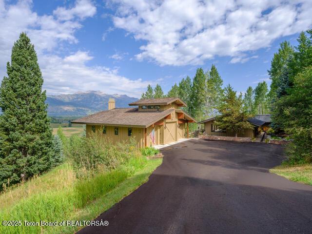 750 N Bar Y Rd, Jackson, WY 83001 - view of front of house with driveway, a chimney, and a mountain view